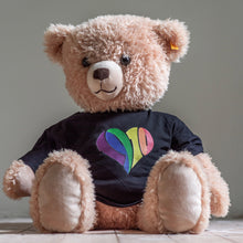 Lade das Bild in den Galerie-Viewer, Auf dem Bild sieht man einen hellbraunen Teddybären. Dieser trägt einen schwarzen Babybody mit einem regenbogenfarbenen 1910 Herz Aufdruck.