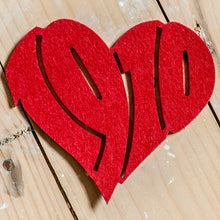 Lade das Bild in den Galerie-Viewer, Auf dem Foto sieht man einen Holzfußboden. Auf diesem befindet sich ein roter Filzuntersetzer. Dieser ist herzförmig ausgestanzt und die Zahl 1910 zu erkennen.