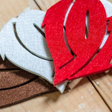 Lade das Bild in den Galerie-Viewer, Auf dem Foto sieht man einen Holzfußboden. Auf diesem befinden sich drei Filzuntersetzer. Der linke ist braun, der in der Mitte weiß und der rechte rot. Die Filzuntersetzer sind herzförmig und die Zahlen 1910 ausgestanzt.