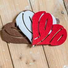 Lade das Bild in den Galerie-Viewer, Auf dem Foto sieht man einen Holzfußboden. Auf diesem befinden sich drei Filzuntersetzer. Der linke ist braun, der in der Mitte weiß und der rechte rot. Die Filzuntersetzer sind herzförmig und die Zahlen 1910 ausgestanzt.