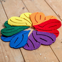 Lade das Bild in den Galerie-Viewer, Auf dem Foto sieht man einen Holzfußboden. Auf diesem befinden sich sechs Filzuntersetzer. Es ist ein gelber, ein oranger, ein roter, ein lila, ein blauer und ein grüner Untersetzer. Diese sind kreisförmig und regenbogenfarben angeordnet. Jeder Untersetzer ist herzförmig ausgestanzt und die Zahl 1910 zu erkennen.