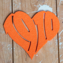 Lade das Bild in den Galerie-Viewer, Auf dem Foto sieht man einen Holzfußboden. Auf diesem befindet sich ein oranger Filzuntersetzer. Dieser ist herzförmig ausgestanzt und die Zahl 1910 zu erkennen.