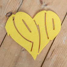 Lade das Bild in den Galerie-Viewer, Auf dem Foto sieht man einen Holzfußboden. Auf diesem befindet sich ein gelber Filzuntersetzer. Dieser ist herzförmig ausgestanzt und die Zahl 1910 zu erkennen.