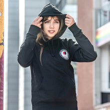 Lade das Bild in den Galerie-Viewer, Ihr seht auf dem Bild 1 Model beim Kapuze aufsetzen. Der schwarze Kapuzenpulli hat den Pocketprint Kein Wein den Faschisten sowie 1910 Weinbar St.Pauli und einem roten und einem schwarzen Weinglas. In Anlehnung an das klassische Antifa Logo. Das Foto entstand vor der Gegengerade des Millerntor Stadions. Heimat des FC St.Pauli.