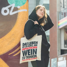 Lade das Bild in den Galerie-Viewer, Auf dem Bild sieht man ein Model angelehnt an eine bunte Wand. Über der rechten Schulter trägt sie einen naturfarbenen Jutebeutel mit dem Aufdruck Das Leben ist zu kurz um unpolitischen Wein zu trinken. Kein Wein den Faschisten. Das Foto entstand vor dem Millerntor Stadion. Heimat des FC St.Pauli.