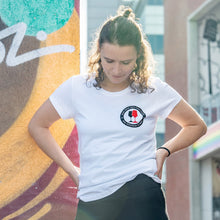 Lade das Bild in den Galerie-Viewer, Auf dem Foto sieht man ein Model vor einer bunten Wand. Sie trägt ein tailliertes, weißes Shirt mit dem Aufdruck Kein Wein den Faschisten sowie 1910 Weinbar St.Pauli und einem schwarzen und einem roten Weinglas. In Anlehnung an das klassische Antifa Logo. Das Bild entstand vor der Gegengerade des Millerntor Stadions. Heimat des FC St.Pauli.