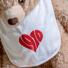 Lade das Bild in den Galerie-Viewer, Auf dem Bild sieht man einen hellbraunen Teddybären. Dieser trägt ein weißes Lätzchen mit dem roten Aufdruck 1910. Die Zahlen sind herzförmig angeordnet.
